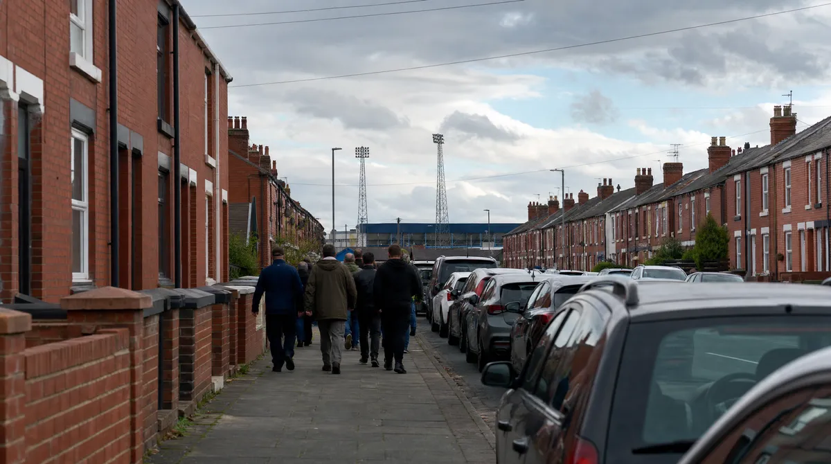 Football supporters walking along a terraced street towards the ground on match day